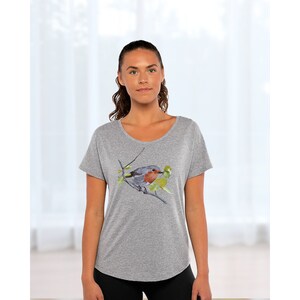 Puede incluir: Una camiseta gris jaspeada con una ilustraci&oacute;n de acuarela de un petirrojo posado en una rama con hojas verdes.