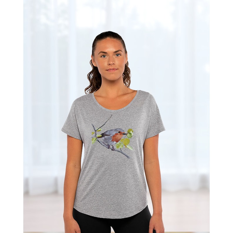 Puede incluir: Una camiseta gris jaspeada con una ilustraci&oacute;n de acuarela de un petirrojo posado en una rama con hojas verdes.