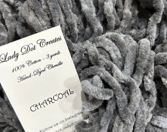 May include: A close-up of charcoal gray chenille yarn, a soft, fuzzy, hand-dyed yarn made of 100% cotton. The yarn is 3 yards long and is perfect for crocheting or knitting.