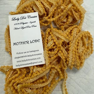 May include: Mustard yellow pom-pom trim with a textured, beaded appearance. The trim is made of 100% polyester and is hand-dyed. A tag reads "Lady Dot Creates" and "MOTHER LODE".