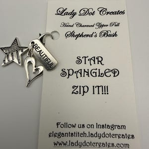 May include: A silver-toned metal zipper pull featuring a star, a heart, and a rectangular charm engraved with the word BEAUTIFUL. The charm is attached to a white display card printed with Lady Dot Creates, Shepherd's Bush, STAR SPANGLED ZIP IT!!!