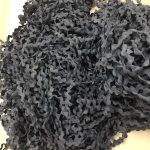 May include: A close-up of a pile of dark gray, wavy trim. The trim is made of a soft, flexible material and has a slightly textured surface.