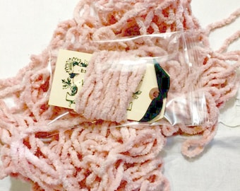 May include: A close-up of a pink fuzzy yarn in a clear plastic bag. The yarn is in a tangled pile and is ready to be used for crafting projects.