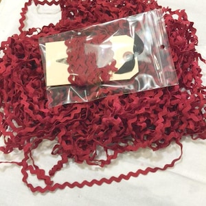 May include: A large quantity of red, zig-zag trim in a clear plastic bag. The trim is packaged with a white tag that says "Handmade with Love".