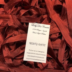May include: A pile of rusty gate colored hand-dyed rayon ribbon. The ribbon is 100% rayon and is 3 yards long. The ribbon is hand-dyed and is a beautiful rusty gate color. Lady Dot Creates 100% Rayon - 3 yards Hand-Dyed Ribbon Rusty Gate Follow us on Instagram elegant stitch.ladydotercreates www.ladydotergates.com ladydotergates@gmail.com