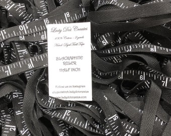 May include: A pile of black and white twill tape with a white card that reads "Lady Dot Creates 100% Cotton - 2 yards Hand-Dyed Twill Tape Black/White Ruler Half Inch Follow us on Instagram elegantstitch.ladydotergates www.ladydotergates.com"