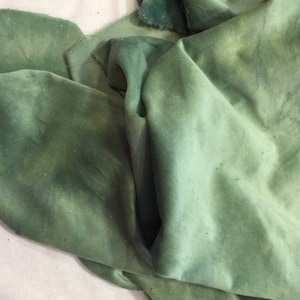 May include: A piece of green fabric with a subtle ombre effect. The fabric is soft and has a slightly textured surface.