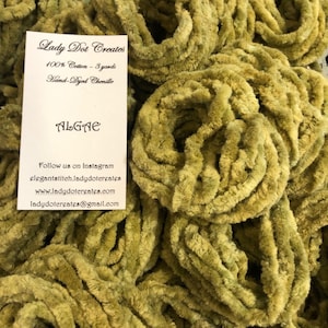 May include: A close-up of a pile of hand-dyed chenille yarn in a green color called "Algae". The yarn is 100% cotton and comes in 3-yard skeins. The image includes a business card with the name "Lady Dot Creates" and contact information.