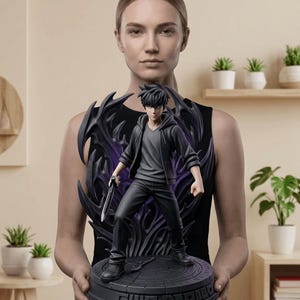 May include: A black and grey statue of a male anime character holding a sword, set against a dark, stylized backdrop. The figure is on a circular base with the text "GUID BADMED". The statue is held by a person.