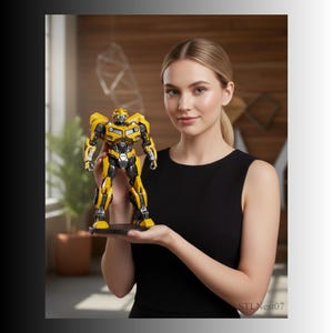Può includere: Action figure di Bumblebee gialla e nera, in piedi su una base nera. La figura presenta dettagli meccanici ed è in posizione eretta. La figura è tenuta davanti a una persona che indossa un top nero.