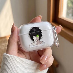 May include: A clear protective case for wireless earbuds featuring a graphic print of an anime character with black hair and a glowing green eye. The case includes a silver-toned metal carabiner clip attached to the side for secure carrying.