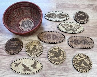 May include: A woven basket with a red rim and a decorative wooden base, surrounded by various wooden oval and circular cutouts. The cutouts feature engraved designs of a butterfly, crab, birds, and floral patterns.