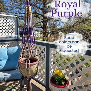 May include: A macrame plant hanger in royal purple and beige, holding a terracotta pot. The text "Royal Purple" and "Bead colors can be requested" are visible. The plant hanger is suspended on a deck with a blue cushion.