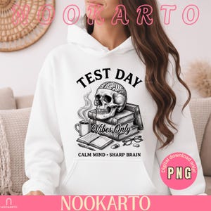 May include: White hoodie featuring a graphic with a skull, brain, books, and coffee cup. Text includes "TEST DAY", "Vibes Only", and "CALM MIND • SHARP BRAIN". The design is in black and white.