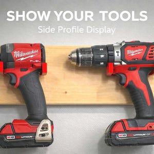 May include: Two red and black Milwaukee power tools are displayed on a wooden plank against a gray background. The tools include a drill and an impact driver, both with the brand name prominently displayed. The text "SHOW YOUR TOOLS" and "Side Profile Display" are at the top.
