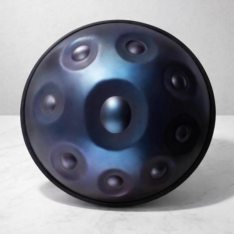 May include: A steel handpan drum with a dark blue and purple iridescent finish. The instrument has a circular shape with multiple dimples and a black rim. The handpan is designed for melodic percussion.