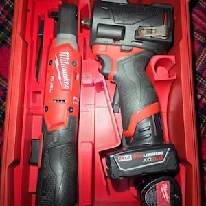 May include: A red and black Milwaukee M12 Fuel cordless ratchet and a compact impact wrench with an attached M12 Redlithium XC3.0 battery, stored inside a molded red plastic carrying case with an additional battery component visible at the bottom.