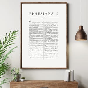 Puede incluir: Impresión enmarcada de Efesios 6 de la Santa Biblia. El texto es negro sobre fondo blanco, con el título en la parte superior. El marco es de color marrón oscuro. La impresión se muestra sobre una superficie de madera.