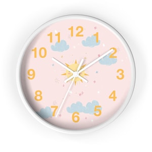 May include: A round wall clock with a white frame and a light pink face. The clock face features a yellow sun, blue clouds, and yellow numbers. The clock hands are white.