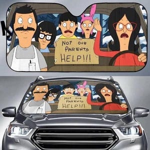 May include: Car sunshade featuring a cartoon family in a car, with the text "Not our parents HELP!!!" on a sign. The characters have exaggerated features and expressions, with one waving.