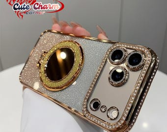 May include: A bedazzled phone case with a gold-colored frame and a glittery silver and pink back. The case features a gold ring holder and is embellished with small, clear rhinestones around the camera lenses. The text "Cute Charm Corner" is visible.