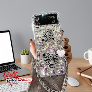 May include: Clear phone case with a leopard design, embellished with rhinestones and a silver chain. The case features a black and white leopard face and a heart-shaped charm. The phone screen displays the time.