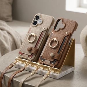 Könnte beinhalten: Zwei strukturierte Handyhüllen in Beige und Braun, jeweils mit Kartenhalter, goldenem Ringständer, Druckknopfverschluss und einem abnehmbaren, passenden Riemen mit goldenen Metallverschlüssen und Beschlägen ausgestattet.