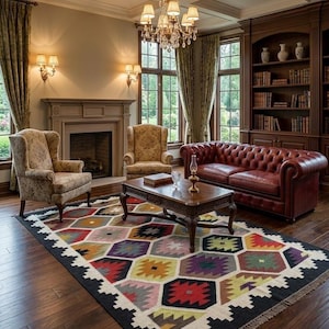 Könnte beinhalten: Ein luxuriöses Wohnzimmer mit einem roten Chesterfield-Sofa aus Leder, gemusterten Sesseln und einem farbenfrohen geometrischen Teppich. Ein Couchtisch aus dunklem Holz steht vor dem Sofa. Der Raum wird von einem Kronleuchter und Wandleuchten beleuchtet.