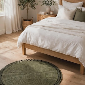 May include: A round, olive green braided rug featuring a decorative looped edge. The rug is constructed from thick, textured fibres arranged in a circular pattern, creating a distinct border detail that frames the central woven surface.