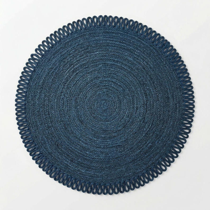 May include: A circular, deep navy blue rug featuring a tightly woven, concentric braided texture. The outer edge is finished with a decorative border of repeating, uniform loops that create a scalloped effect around the entire perimeter.