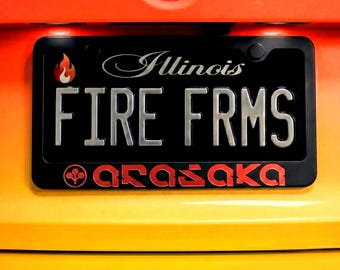 Op de afbeelding: Zwarte nummerplaat met de tekst "FIRE FRMS" in zilver en "Illinois" in zilveren letters. Een vlammenafbeelding staat in de linkerbovenhoek. Het woord "arasaka" staat in het rood onderaan. De achtergrond is geel en oranje.