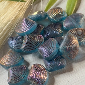 May include: A collection of iridescent blue glass beads shaped like seashells with a metallic copper finish.