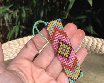 May include: A colorful beaded bracelet with a geometric pattern in shades of pink, orange, turquoise, brown, and black.