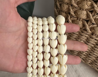 May include: Five strands of off-white beads, each shaped like a small tulip flower with vertical carved lines. The beads are arranged in varying sizes, with the strands on the left featuring smaller beads and the right featuring larger beads.