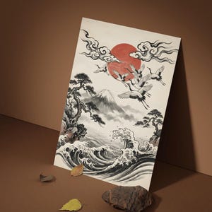 Peut inclure: Une œuvre d'art d'inspiration asiatique représentant un soleil rouge, des grues en vol et un paysage de montagne. La peinture représente des vagues océaniques, des arbres et des nuages dans des tons de noir, blanc et gris. L'œuvre est exposée sur une surface marron.