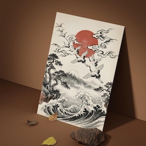 Puede incluir: Lámina artística de inspiración japonesa con un sol rojo, grullas volando y un paisaje montañoso. La obra está realizada en blanco y negro con sombreado gris, evocando una estética tradicional. La impresión se apoya sobre un fondo marrón.