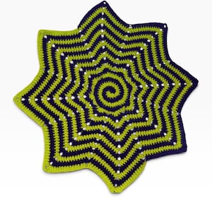 May include: A star-shaped crochet doily featuring a spiral center pattern. The textile is crafted with alternating rows of dark purple and lime green yarn, creating a geometric, multi-pointed design with small openwork holes throughout the piece.