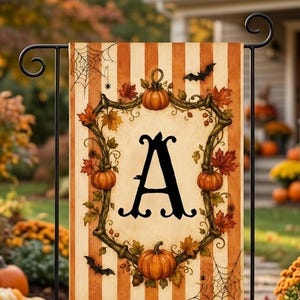 May include: A rectangular garden flag featuring a vertical orange and cream striped background. The center displays a large black letter A surrounded by a decorative vine wreath with orange pumpkins, autumn leaves, spiderwebs, and black bats.