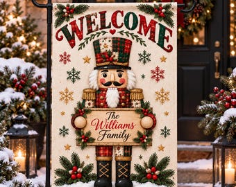 Könnte beinhalten: Eine rechteckige Gartenflagge mit dem Wort WELCOME in roten und grünen Buchstaben oben. Eine zentrale Nussknackerfigur in karierter Uniform hält ein Holzschild mit der Aufschrift The Williams Family. Das Design enthält Schneeflocken und Kiefer.