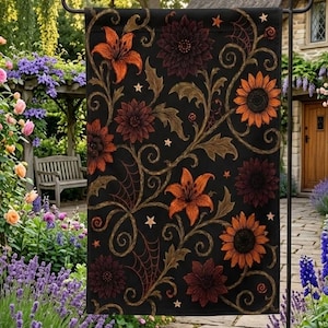 May include: A rectangular garden flag featuring a black background with a repeating pattern of orange lilies, dark red dahlias, and orange sunflowers. The design includes swirling vine motifs, small five-pointed stars, and spider web accents.