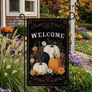 May include: A rectangular garden flag with a black background featuring the word WELCOME in white capital letters. The design includes a cluster of white, dark green, and orange pumpkins surrounded by small orange and white flowers and foliage.