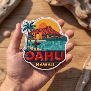 May include: An embroidered patch featuring a tropical landscape with a palm tree, a surfer on a beach, a mountain, and a sun. The text OAHU is in large red letters, with HAWAII in smaller yellow letters below on a dark brown background.