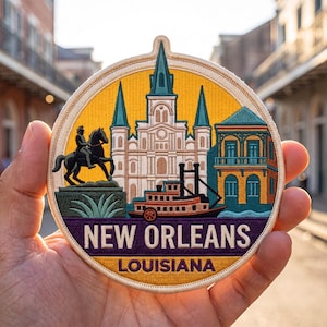 May include: A circular embroidered patch featuring a yellow background with a white cathedral, a teal building, a black statue of a person on a horse, and a brown steamboat. The text NEW ORLEANS and LOUISIANA is stitched in white and yellow.