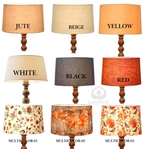 May include: Nine lamps with wooden bases and various shades. The shades are labeled: JUTE, BEIGE, YELLOW, WHITE, BLACK, RED, MULTICOLOR-01, MULTICOLOR-02, and MULTICOLOR-03. The lampshades have different colors and patterns.