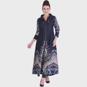 Könnte beinhalten: Ein langärmeliges, bodenlanges Mantelkleid in Marineblau mit durchgehendem Frontreißverschluss, spitzem Kragen und einem detaillierten weiß-hellblau-dunkelblauen Muster am Saum und an den Ärmeln sowie zwei kleinen Knöpfen im Brustbereich.