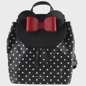 May include: Black and white polka dot backpack with a red bow and mouse ears. The backpack has a top handle and adjustable straps. The brand name "kate spade new york" is visible on the front.