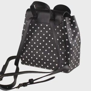 May include: Black backpack with white polka dots. The backpack has adjustable straps and a top handle. The bag features a flap closure and a drawstring closure. The backpack is made of a durable material.