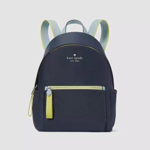 Puede incluir: Mochila azul marino con detalles en azul claro y amarillo. Cuenta con un bolsillo frontal con cremallera y un asa superior. El texto "kate spade NEW YORK" está impreso en la parte delantera.