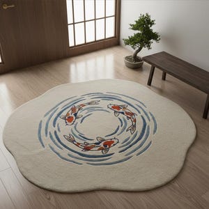 May include: A round, off-white rug featuring a koi fish design. Three orange and white koi fish swim in a circle within blue water ripple patterns. The rug has a unique, organic shape, adding a touch of nature to any room.
