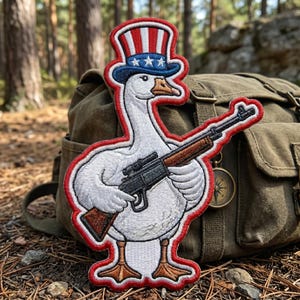 May include: Embroidered patch featuring a white goose wearing a patriotic Uncle Sam hat and holding a rifle. The patch has a red, white, and blue color scheme with a red border. The background includes a green backpack and a compass.
